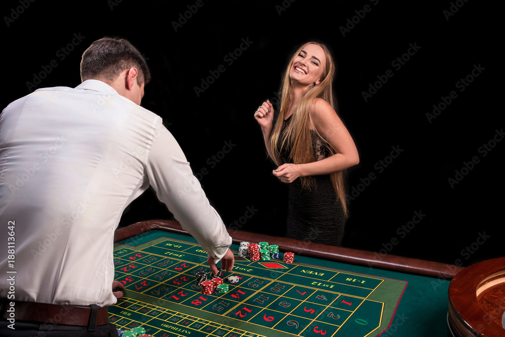 A close-up on the back of the croupier in a white shirt, image of green casino table with roulette and chips, a rich woman betting of gambling in the background A close-up on the back of the croupier in a white shirt, image of green casino table with roulette and chips, a rich woman betting of gambling in the background