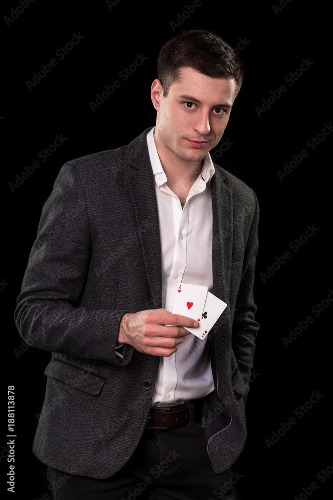 Young caucasian man wearing suit holding two aces in his hand on black background. Gambling concept. Casino Young caucasian man wearing suit holding two aces in his hand on black background. Gambling concept. Casino