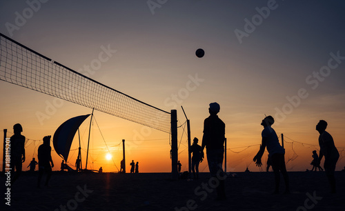 Silhouets of men playing beach volleyball at the evening glory time