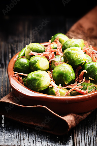 Brussels sprouts with bacon, and caramelised onion on a black rustic table.