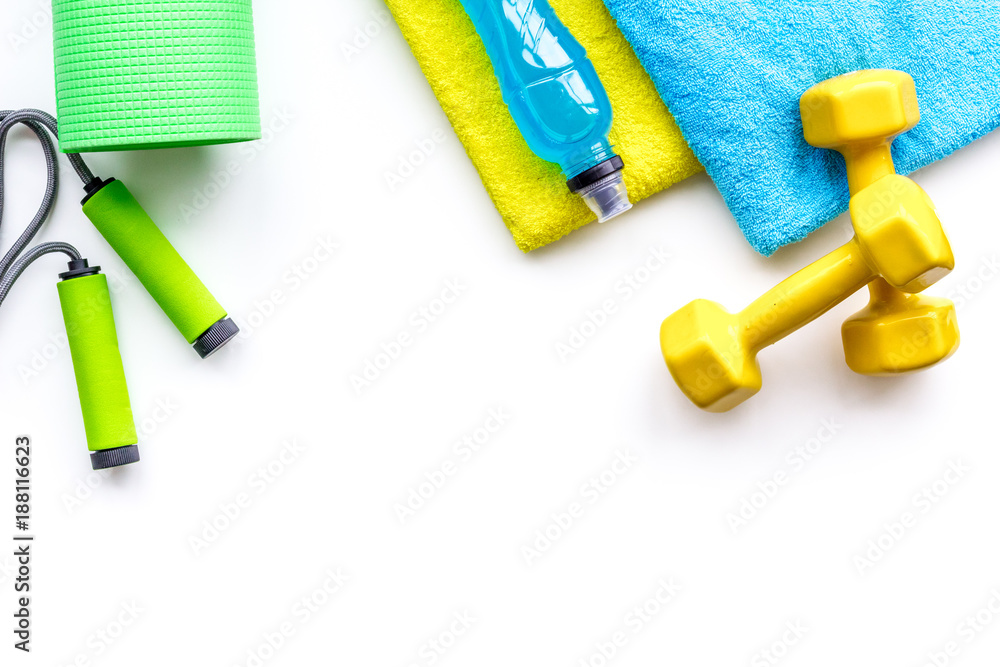 Fitness concept. Sport drink, dumbbells, mat, jump rope, towel on white background top view space for text Fitness concept. Sport drink, dumbbells, mat, jump rope, towel on white background top view space for text