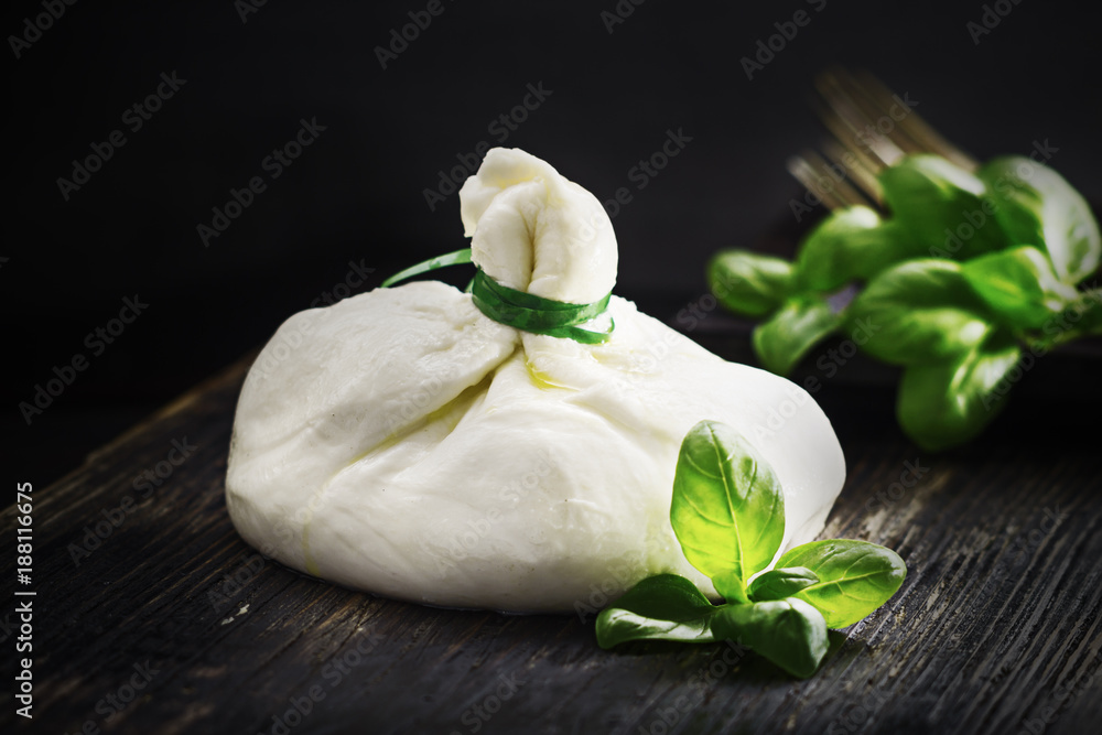 Burrata with basil on black background. Burrata with basil on black background.