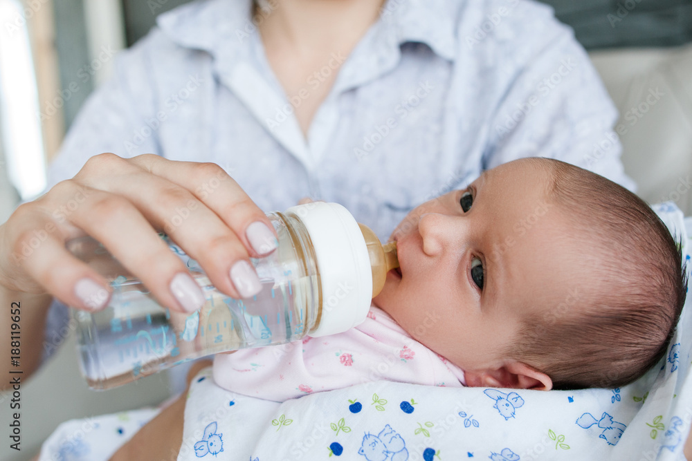 mom gives the newborn baby water from a bottle. feeding time. mother's care mom gives the newborn baby water from a bottle. feeding time. mother's care