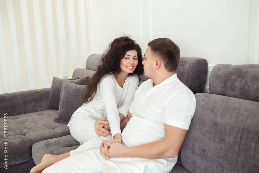 Beautiful couple smiling and hugging while spending time together at home with modern white interior