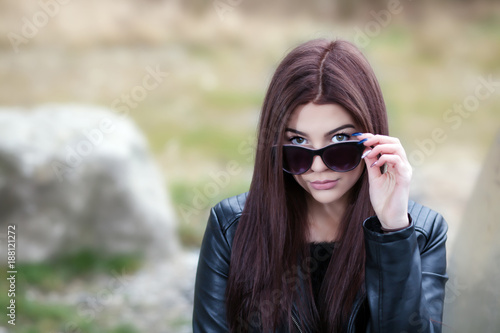Seductive brunette peering over sunglasses