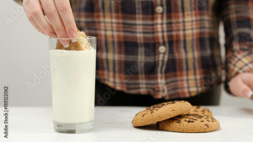 Woman dipping chocolate chip cookie in warm milk. Delicious and healthsome snack photo