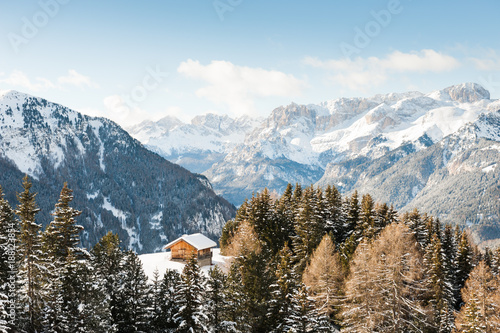 Wooden house in Dolomites at winter sunny day, Val di Fassa ski resort, Italy
