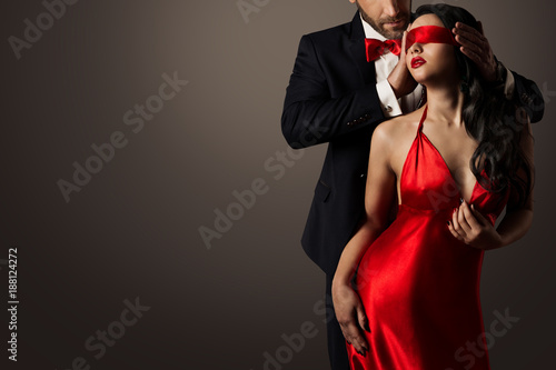 Couple Love Kiss, Sexy Blindfolded Woman Dancing in Red Dress and Elegant Man in Suit photo