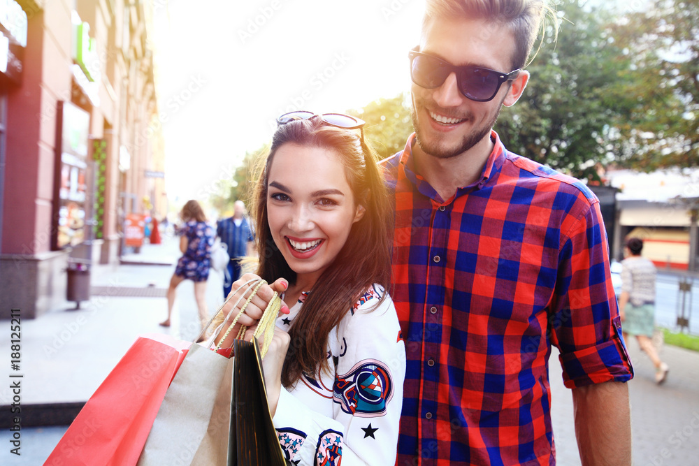 Naklejka premium Young happy couple with shopping bags in the city