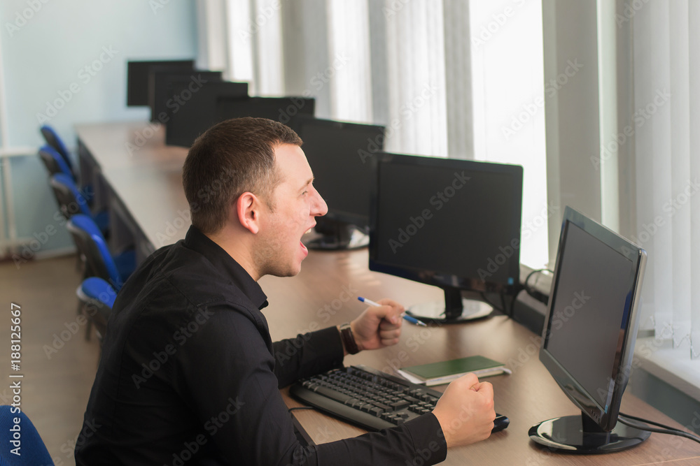 angry business man dressed in a black shirt screaming and beating his fist at the monitor in the workplace angry business man dressed in a black shirt screaming and beating his fist at the monitor in the workplace