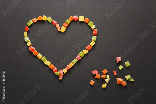 Candied fruits in the form of heart isolated on black background for design. Saint Valentine's Day card on fabruary 14, holiday concept.