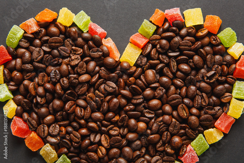 Colorful candied fruits in the form of heart with brown coffee beans isolated on black background for design. Saint Valentine's Day card on fabruary 14, holiday concept. Copy space for advertisement.