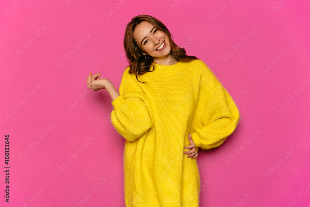 Smiling gorgeous girl, looking at camera, posing. Standing in stylish yellow sweater, on pink background. Concept of Valentine's day. Smiling gorgeous girl, looking at camera, posing. Standing in stylish yellow sweater, on pink background. Concept of Valentine's day.
