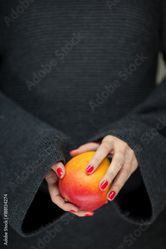 Woman hands holding a mango, sensual studio shot can be used as background