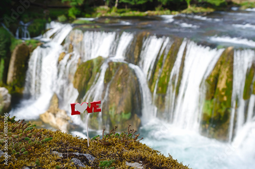 love text on a stick above the waterfall
