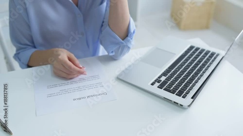 Emotional tiredness. Frustrated female office worker crying and closing her laptop after reading a dismissal notice.