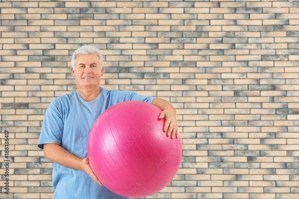 Senior man with fitball on brick wall background Senior man with fitball on brick wall background