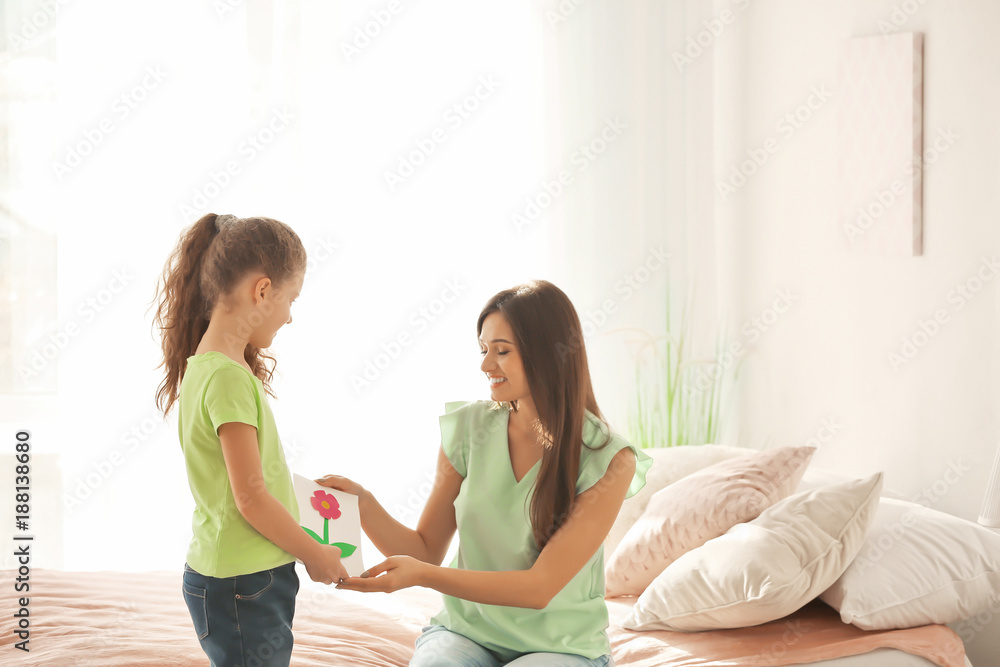 Little girl giving greeting card to her mom. Mother's day celebration