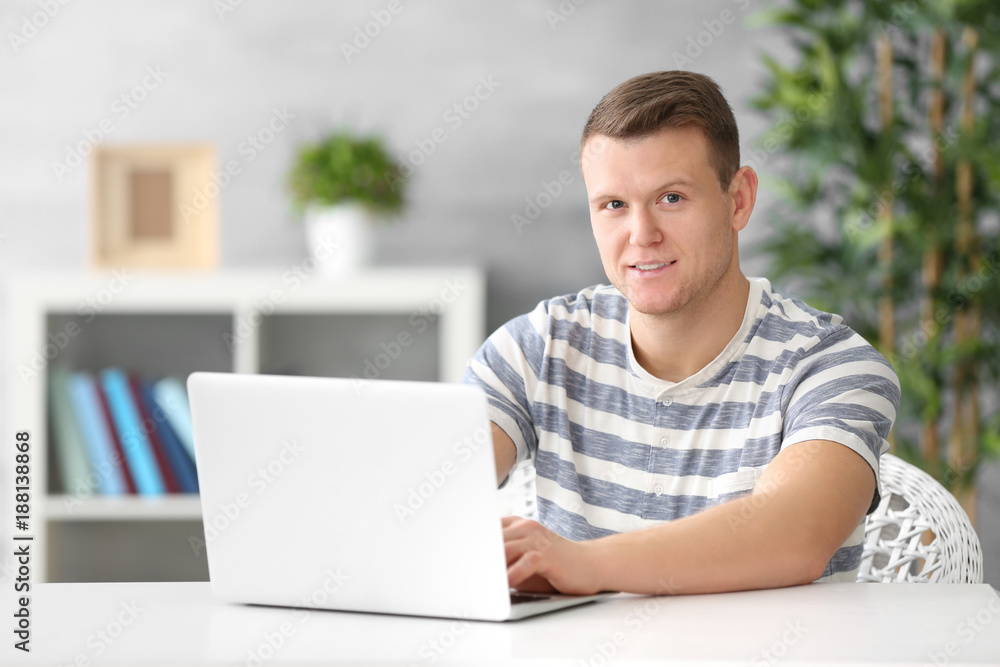 Young man using laptop at table indoors Young man using laptop at table indoors