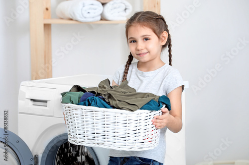 Cute little girl doing laundry at home photo