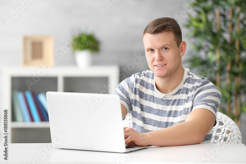 Young man using laptop at table indoors