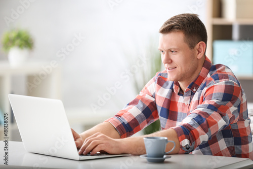 Young man using laptop at t...