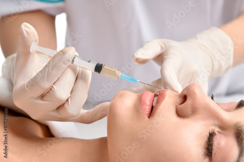 Plastic surgery beauty concept young brunette woman face and doctor hand in glove with syringe