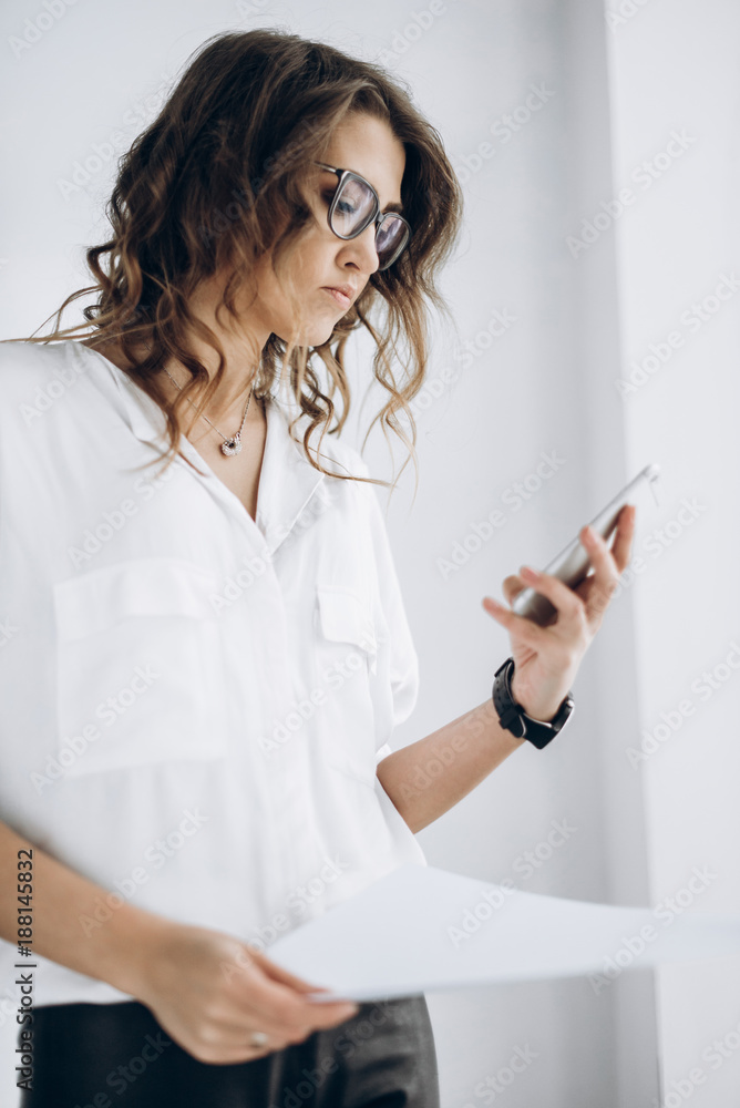 Portrait of a serious business woman which holds her smartphone in her hand and looks at some information Portrait of a serious business woman which holds her smartphone in her hand and looks at some information