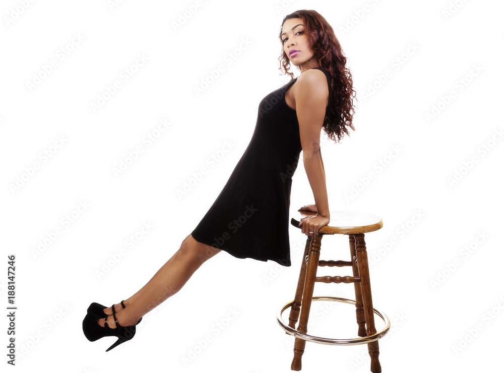 Fototapeta premium Attractive Hispanic Lady In Black Dress Leaning On Stool