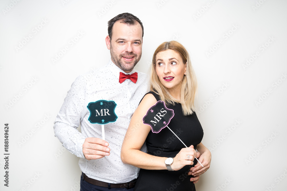 young couple funny props pose photo booth plain background