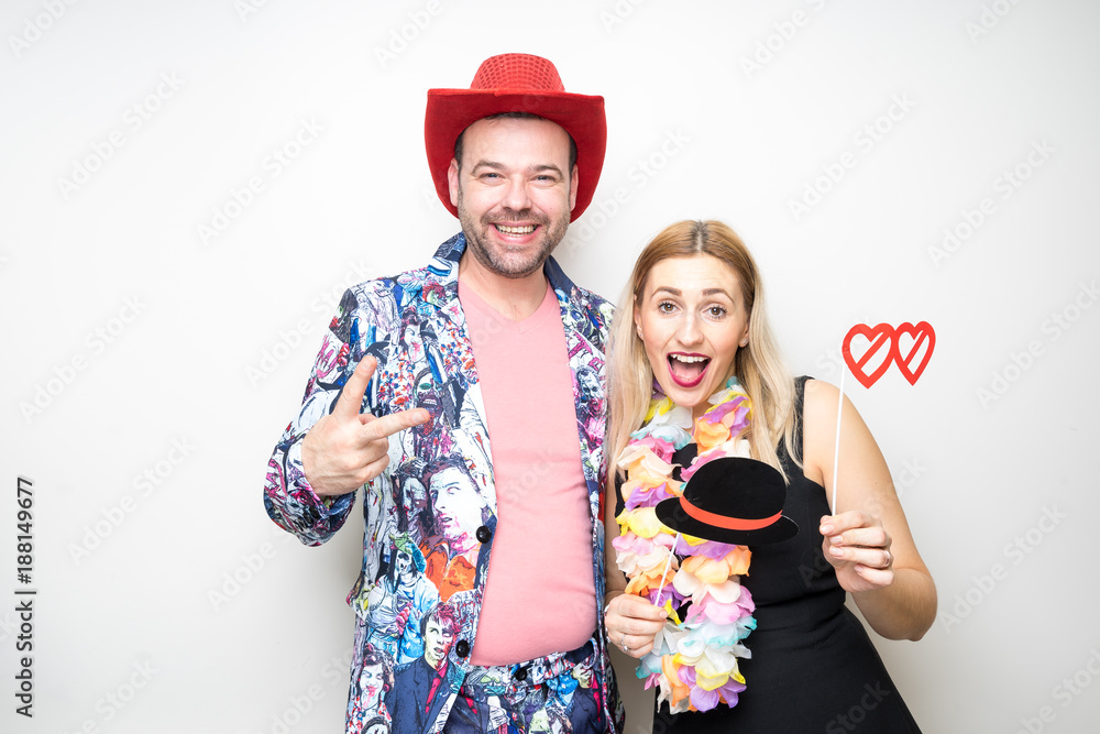 young couple funny props pose photo booth plain background