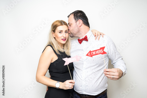 young couple funny props pose photo booth plain background