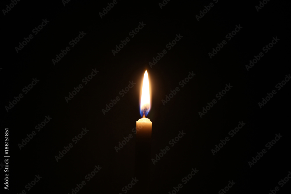 Dark candle light, one light of yellow candle on black background.