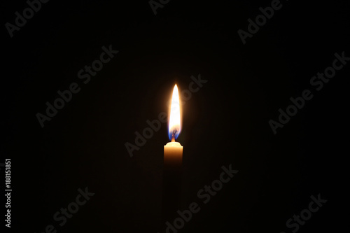 Dark candle light, one light of yellow candle on black background.