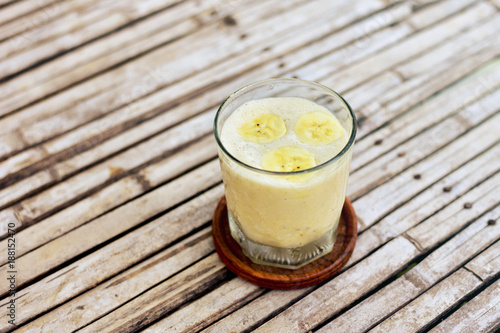Banana smoothie in the glass on the old wooden background