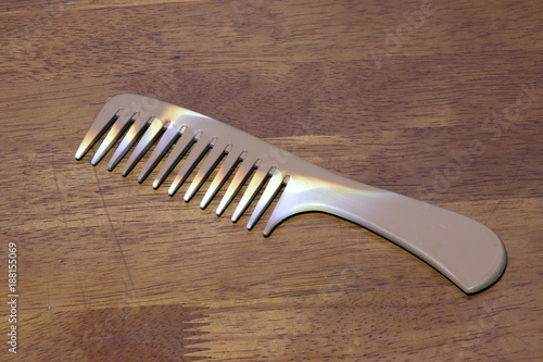 Striped brown color of comb isolated on wooden table background. it is a strip of plastic with a row of narrow teeth, used for untangling or arranging the hair.