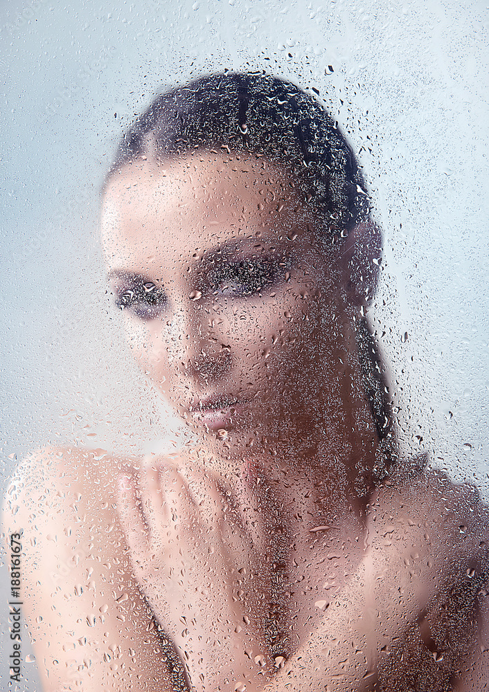 Brunette woman with makeup smoky eyes, folded his arms on the neck with water drops close-up on a light background