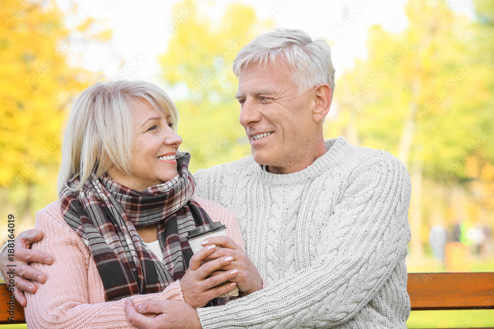 Cute elderly couple sitting on bench in autumn park