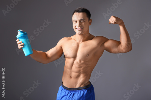 Sporty young man with protein shake on color background