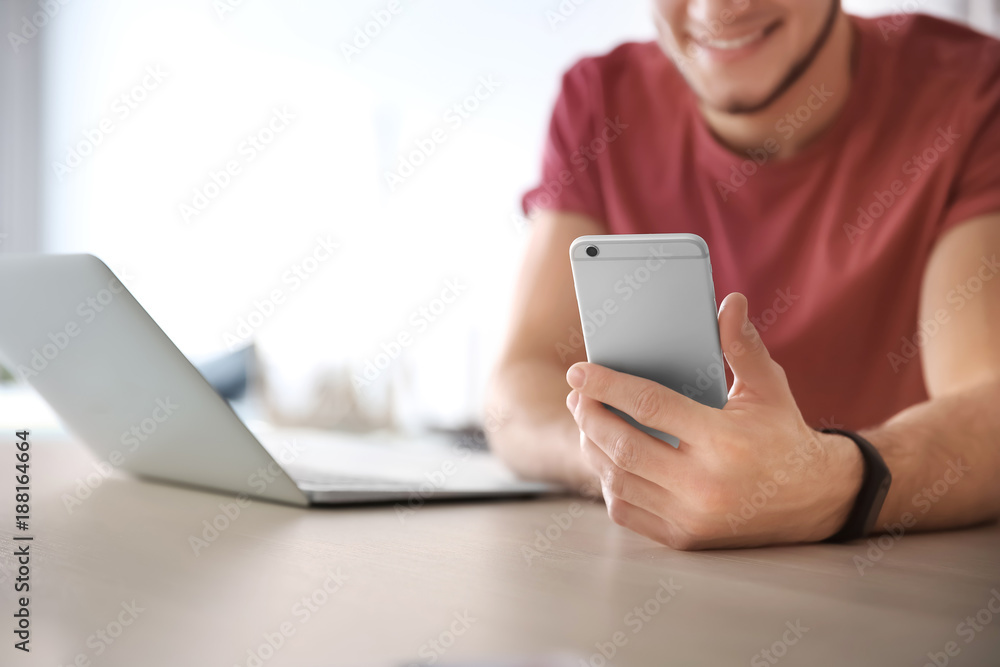 Young man using laptop and mobile phone at home Young man using laptop and mobile phone at home
