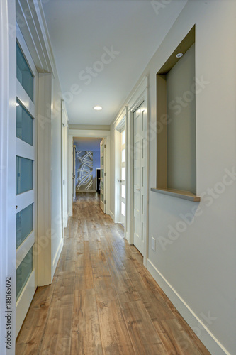 Long  narrow corridor with white doors accented with glass panels