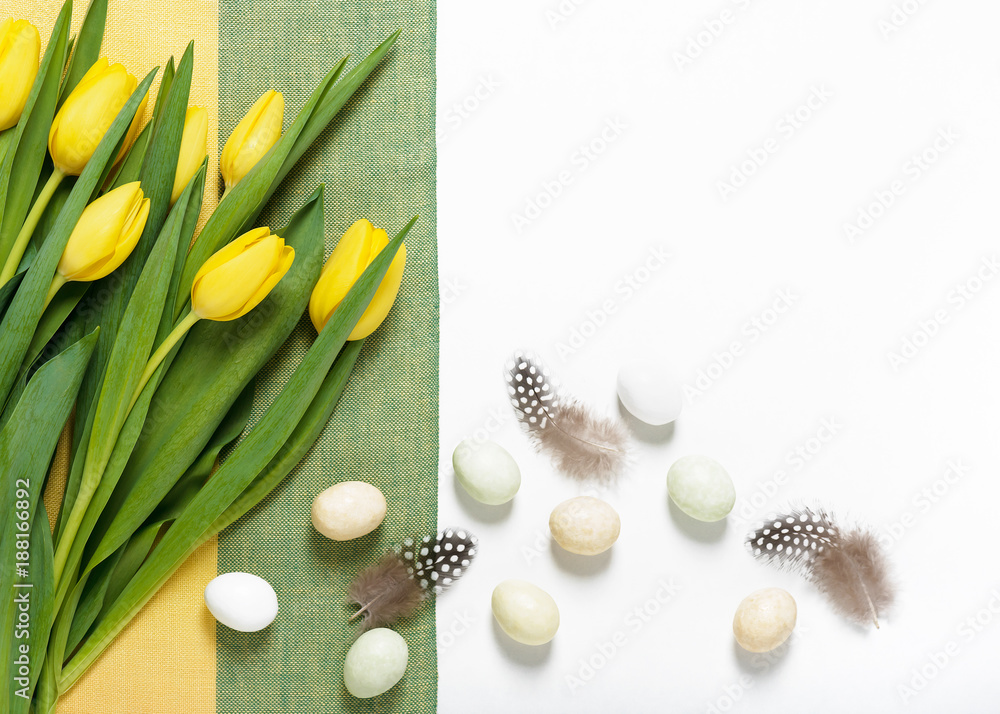 Beautiful yellow tulips on linen tablecloth with eggs and feathers. Easter background. Top view. Copy space. Beautiful yellow tulips on linen tablecloth with eggs and feathers. Easter background. Top view. Copy space.