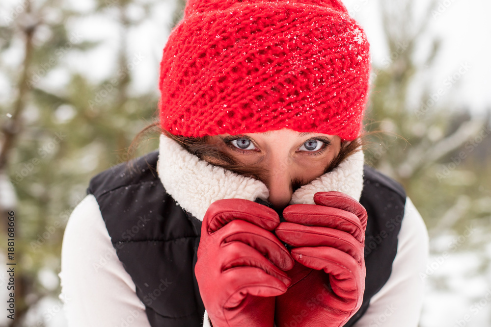 Portrait of girl in a red cap and warm jacket in the forest in a winter Portrait of girl in a red cap and warm jacket in the forest in a winter