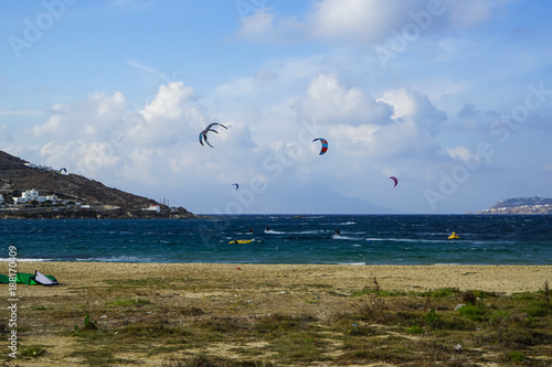 Mykonos, Greece - September 28, 2017: Kitesurfing, kind of extreme windsurf sailing boarding water sports in strong wind at Korfos bay beach with blue sky background