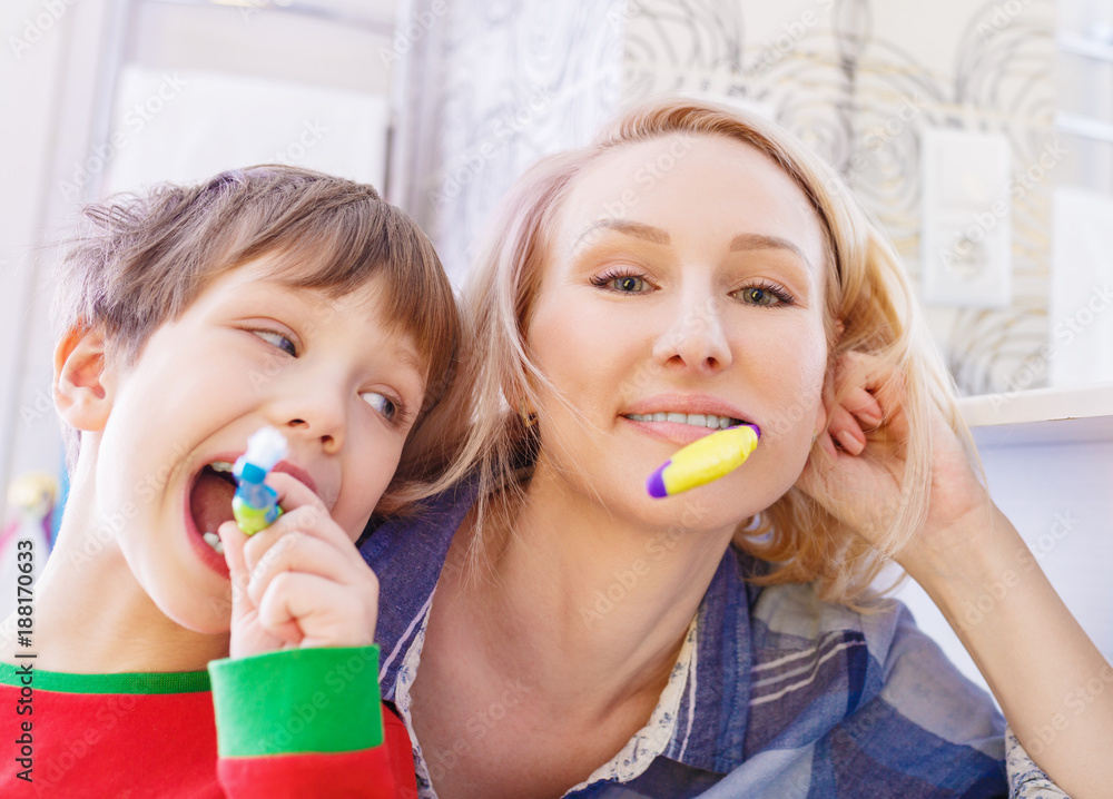 Beautiful happy mother and little son in bathrom brushing teeth together Beautiful happy mother and little son in bathrom brushing teeth together