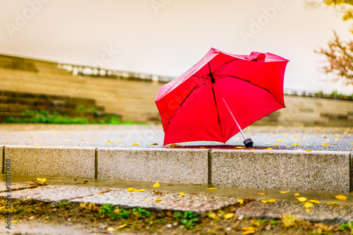 Red umbrella on concrete floor with raining in the park.  vintage image.  lonely concept. copy space for text