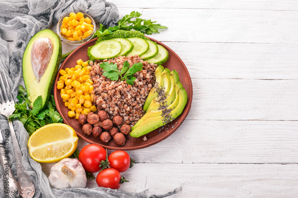 Healthy food. Buckwheat, avocado, cucumber, corn and hazelnut. On a wooden background. Top view. Free space for your text.