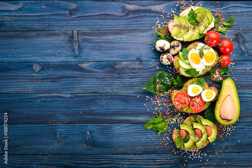 A set of avocado sandwiches, cherry tomatoes and quail eggs and chia seeds. On a wooden background. Top view. Free space for your text.