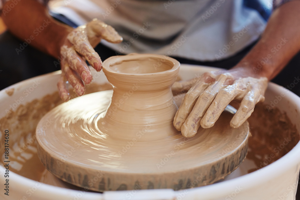 Human hands touching rotating jug in fireclay machine during work Human hands touching rotating jug in fireclay machine during work