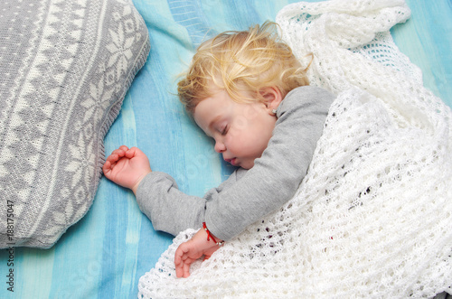 Cute little blonde girl sleeping on the bed photo